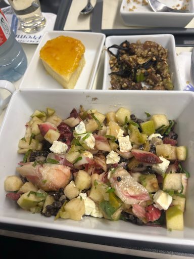 Image fo a tray of food including a salad, a smaller grain salad and a slice of cake