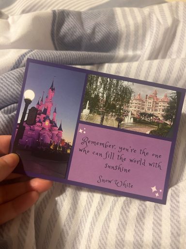 Image of a postcard which has a purple background, image of the castle and the disneyland hotel and a quote from snow white