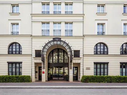 Exterior of the hotel, a cream coloured building with an ironwork arch around the entrance