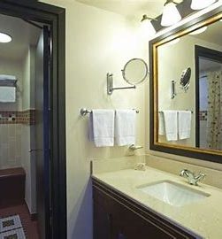 Image of the side of the sink which is a cream worktop with a large mirror above