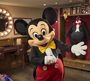 Mickey Mouse in his classic outfit in a room with a dressing table and wardrobe in the background