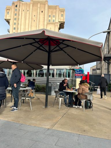 patio area with a parasol and silver tables and chairs