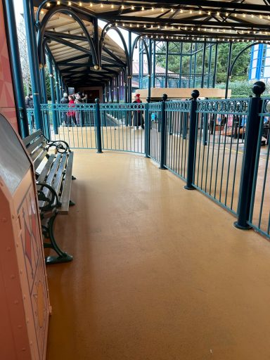 a pale orange smooth floored area with a bench and a green metal fence