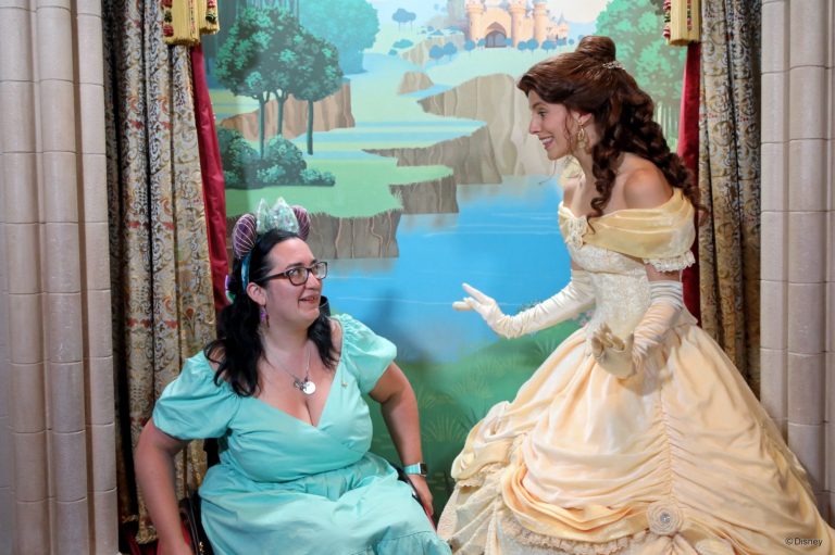 Jody is seated in her chair wearing a turquoise dress and ariel ears, she is chatting to belle