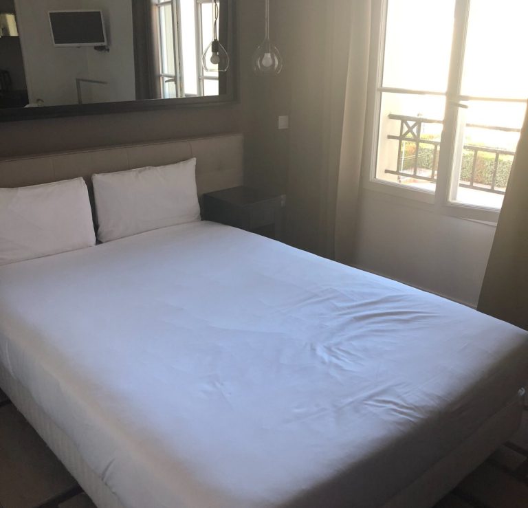 Image of a double bed with a mirror above and bedside tables