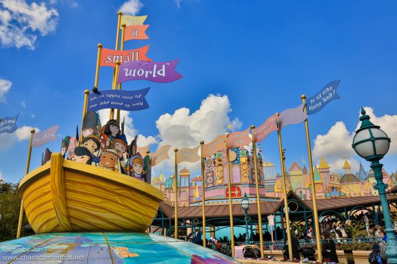 Image shows exterior of It's a small world with a boat atop a globe and colourful flags