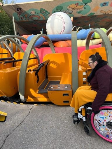 a wheelchair user waiting to board next to the drop down side of the ride vehicle