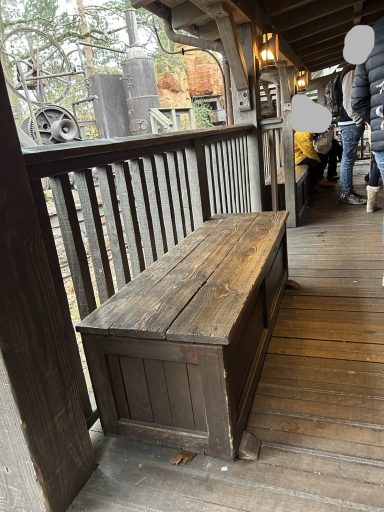 a wooden bench designed to look like a owoden box with a wooden fence behind it