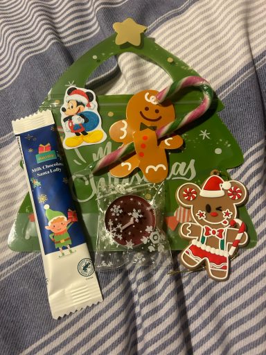 A christmas tree shaped bag with a candy cane, chocolate lolly, tealight, sticker and gingerbread tree decoration 