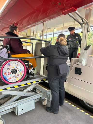 A wheelchair user is on a platform lift raised from the ground