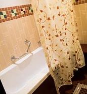 Image of the bath in a standard room with a small grab rail and a shower curtain