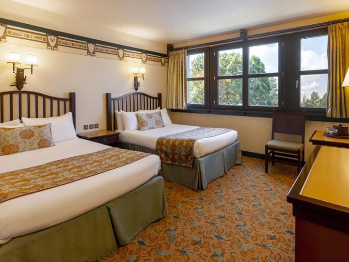 Image of a standard room showing 2 double beds, a tv, dresser, and woodland theming with muted colours and dark wood windows and furniture