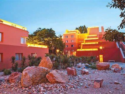 Exterior of the hotel with rocks and dessert plants and terracotta toned buildings