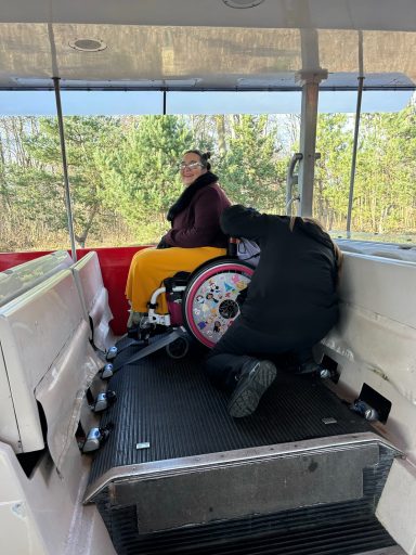 an image of a wheelchair user on board a tram with someone securing the wheelchair