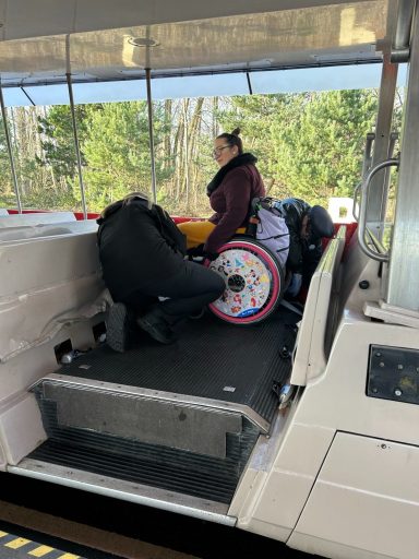 an image of a wheelchair user on board a tram with someone securing the wheelchair