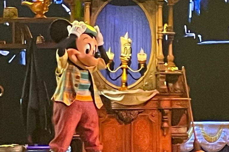 The image shows Mickey on stage, lumiere is on a dresser next to him