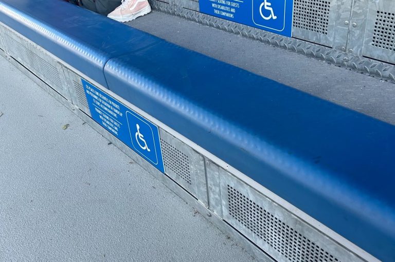 The image shows some blue padded benches marked with the wheelchair symbol