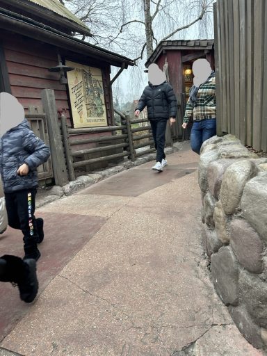 a concrete path with a stone wall on one side and a wooden building on the other side