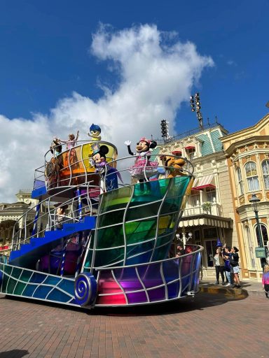 Image shows a colourful float with disney characters riding on it, including Mickey and minnie