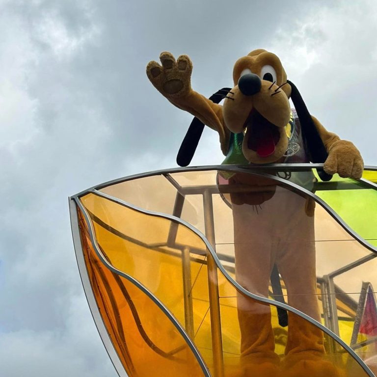 Pluto is aboard a float and waving to the crowds