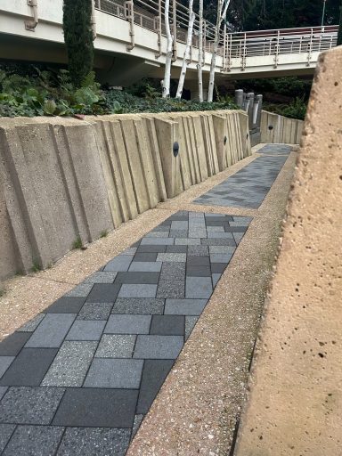 A path with grey stone tiled floor and sandstone coloured walls at either side