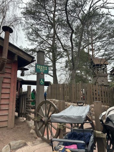 wild west landscape with a wagon wheel fence, there is a post with a sign with a wheelchair symbol on it