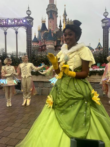 Tiana standing close to us with some gold costumed dancers in the background