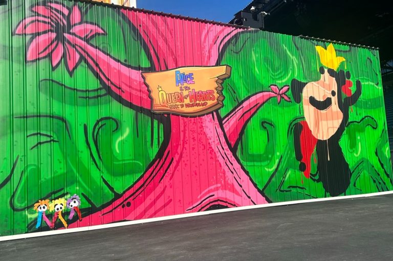 The image shows a a green painted wall with a pink tree and a stylised queen of hearts