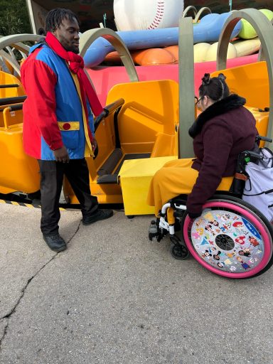 a wheelchair user waiting to board next to the drop down side of the ride vehicle