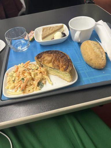 A tray of food including some quicje and coleslaw and a bread roll