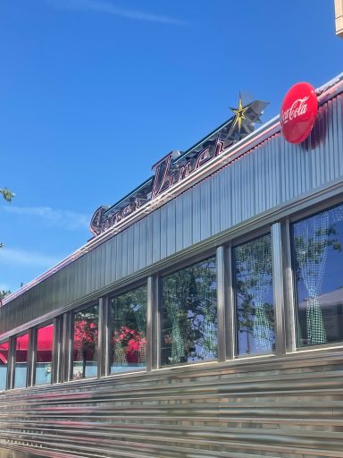 the exterior of the diner, silver meta with windows and a super diner sign