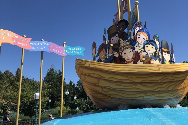 Photo of the outside of the ride where there is a model wooden boat filled with dolls and colourful flags