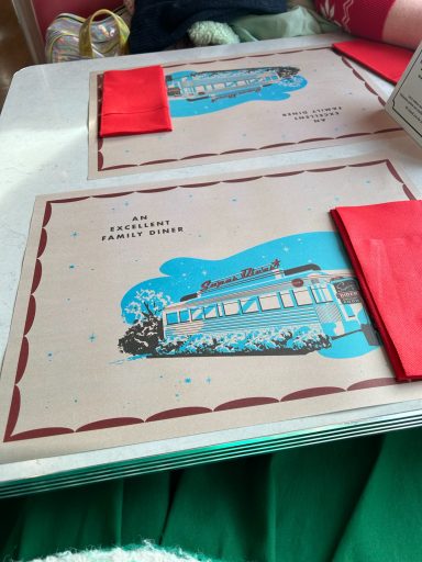 A paper place met and red napkin, the placemat is vintage styled with an image of the diner on it