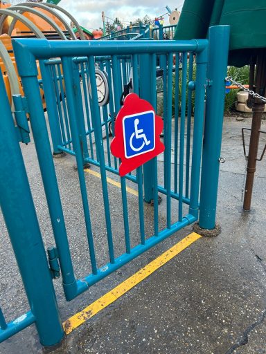 A blue metal gate with a square blue wheelchair sign on it