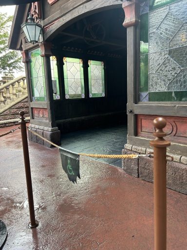 a glass and wooden porch like structure with a rope fence in the foreground