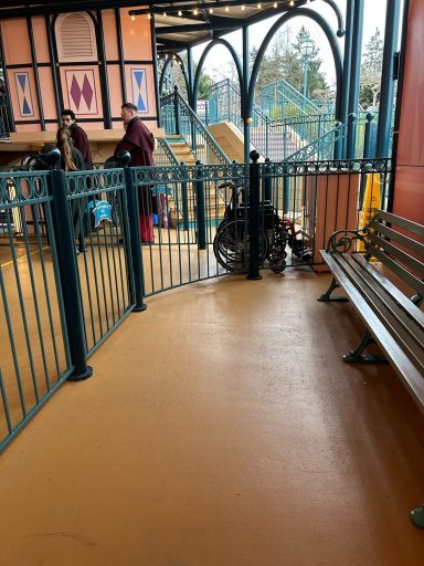 a pale orange smooth floored area with a bench and a green metal fence