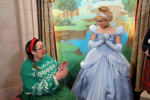 Cinderella is speaking to jody, a brunette seated in her wheelchair wearing a green christmas jumper