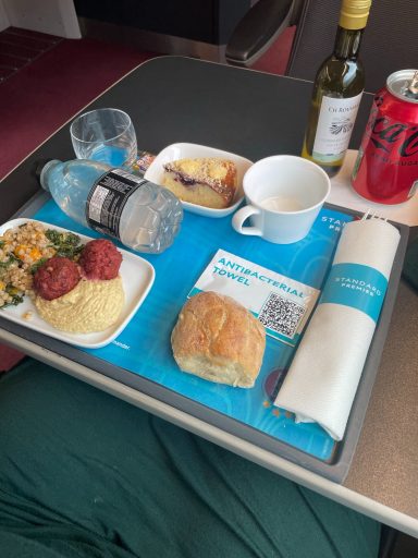 Image of some food items on a tray inclusing a cup, bread roll, grain salad and a dessert