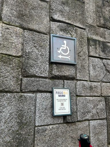 a grey wheelchair symbol sign attached to a stone wall