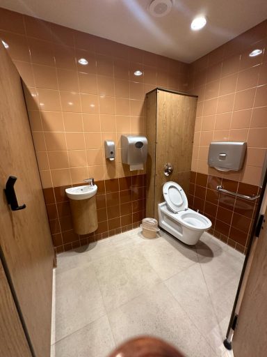 A larger accessible toilet stall with a toilet and sink and a horizontal grab bar