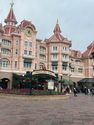 Pale pink Victorian style building with a flowerbed and a Disneyland Park sign