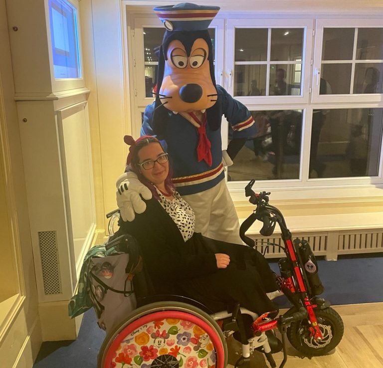 Jody meeting goofy in a sailor outfit while seated in her wheelchair with the handcycle attached