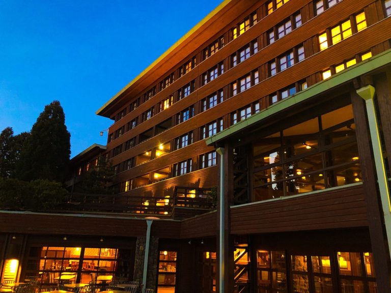 Exterior of the hotel at dusk, with wood cladding exterior and trees