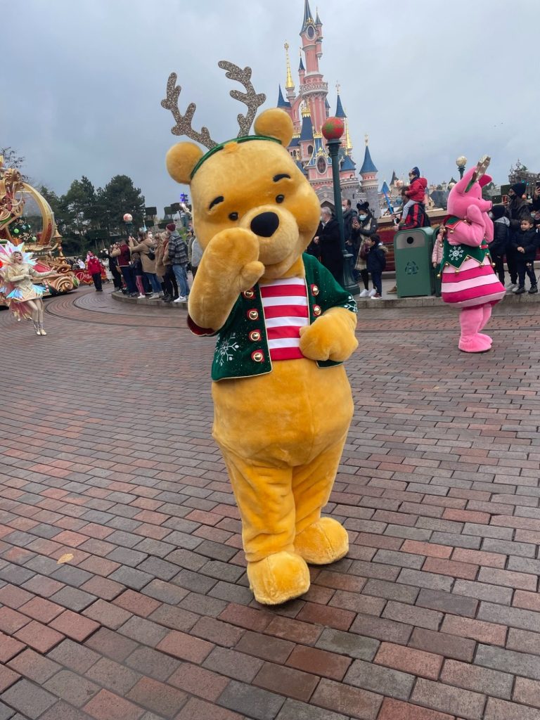 Pooh bear in a festive top waving on the parade route 