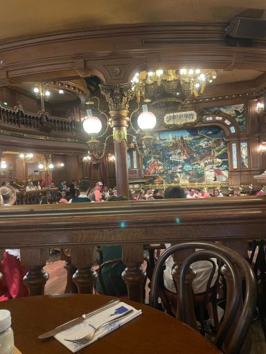 there is a dark brown table in the foreground and some wooden railings then a room with theming to the wild west