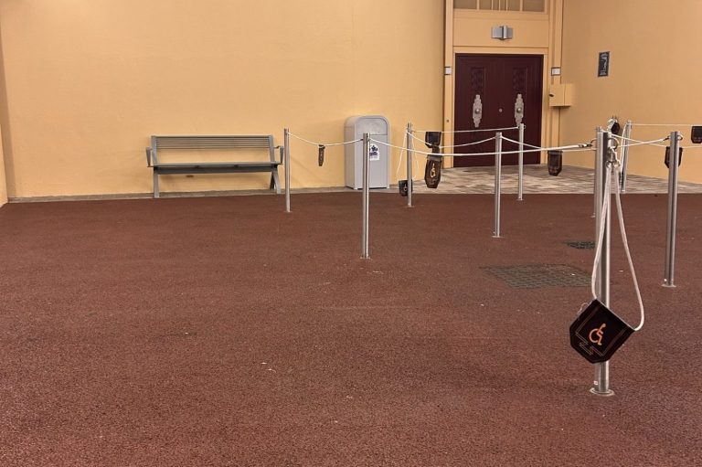 Image shows a red floored waiting area with theatre doors and a single bench