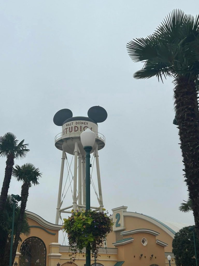 Image of the earful town at walt disney studios, a water tower with mickey ears, and some palm trees framing it