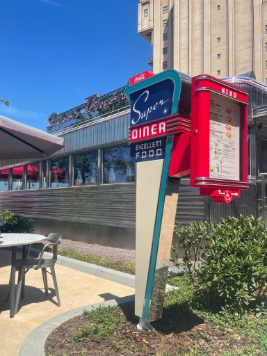 a menu board is mounted on t a triangular stand with super diner written on it