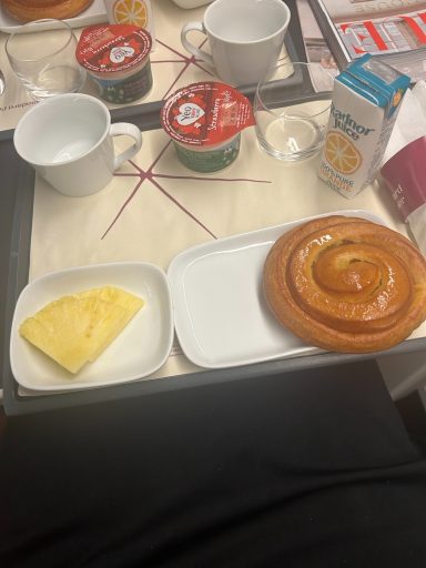 image of breakfast foods on a tray, including a pastry, fruit and a yoghurt