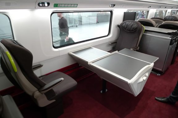 Image showing a table on a train with two seats either side facing each other with wheelchair spaces next to them